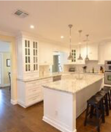 Modern kitchen with white cabinets, marble island, pendant lights, and stools. Open layout with hardwood floors.