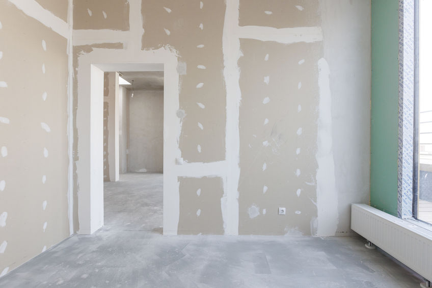 Unfinished room with drywall installation, showing taped seams and a large window on the right.